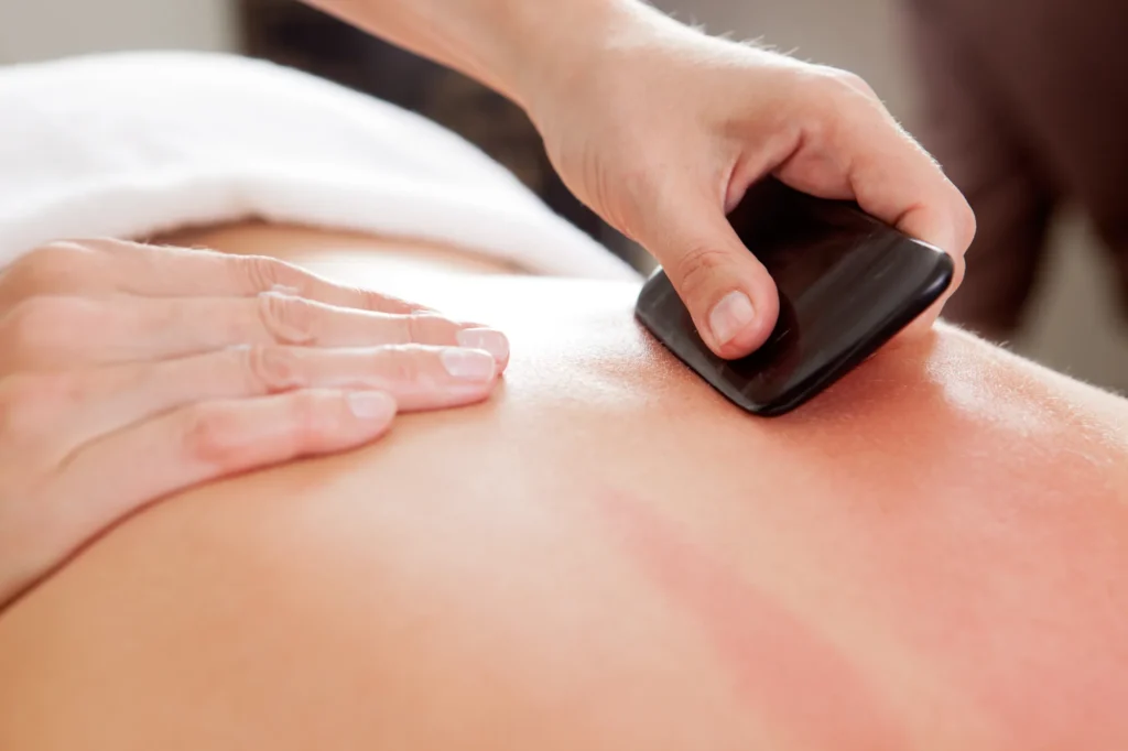 Gua sha-behandeling met een steen op de rug